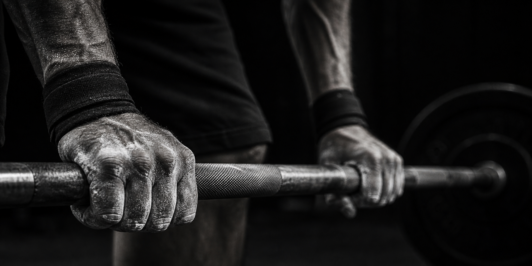 Chalked hands gripping a barbell — the mark of commitment